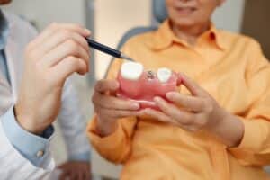 Close up of a dentist explaining how dental crowns work to prevent tooth loss during a consultation