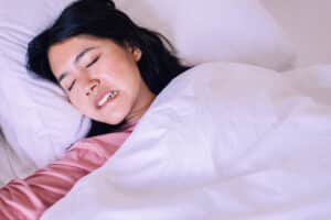 Sleeping young woman grinding her teeth and possible hurting here overall health, in need of treatment