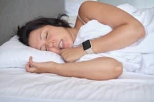 A woman laying in bed asleep while grinding her teeth, in need of bruxism treatment.